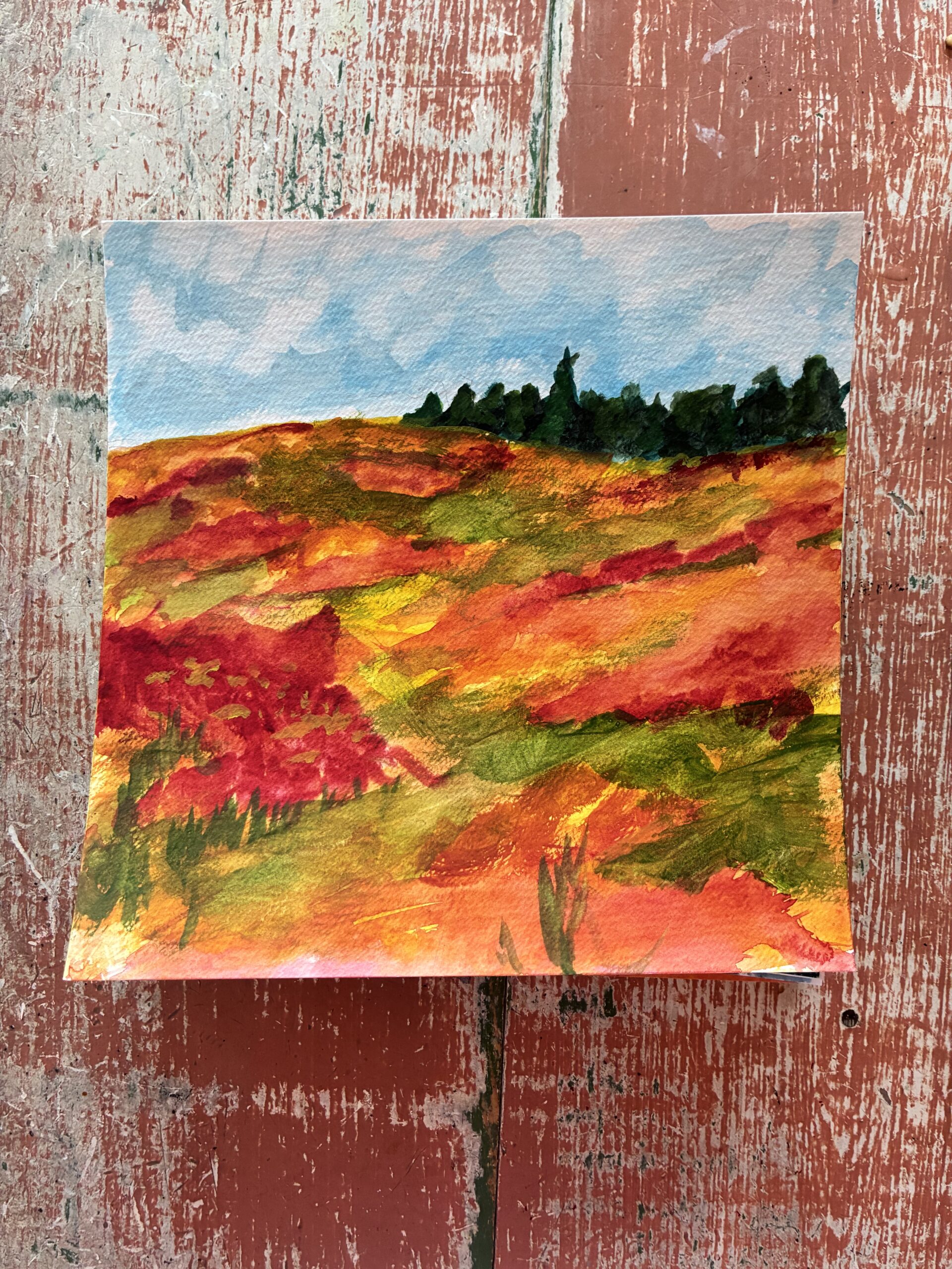 A watercolor painting of a particularly vibrant hill, reds and oranges and greens